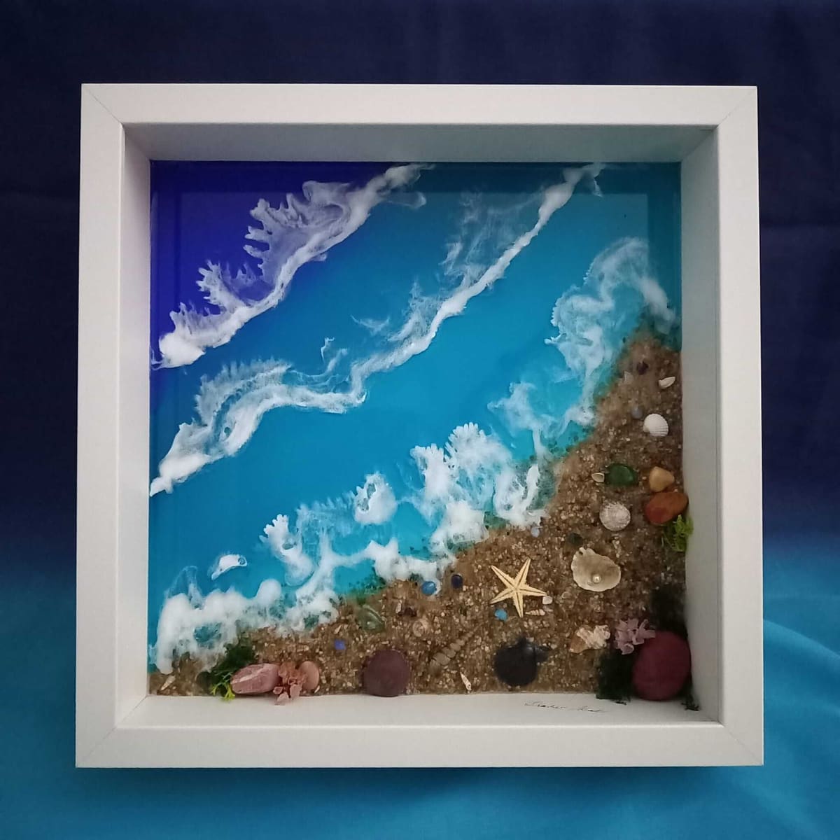 Strandbild aus Epoxidharz im weißen Kastenrahmen: Wellen in Blau und Türkis, Sand und Muscheln