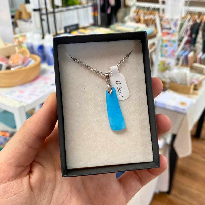 Hellblauer Meerglas-Anhänger an einer Edelstahlkette in einer Schmuckschachtel