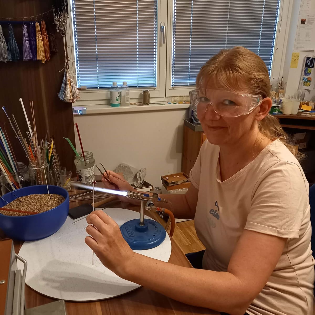 Ulrike Fischer mit Schutzbrille am Brenner beim Glasperlendrehen in ihrer Werkstatt